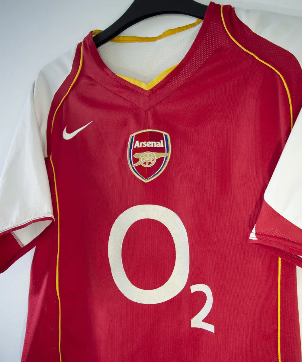 Maillot vintage domicile rouge et blanc d'arsenal de la saison 2004-2005. On peut retrouver le sponsor O2 et l'équipementier nike.