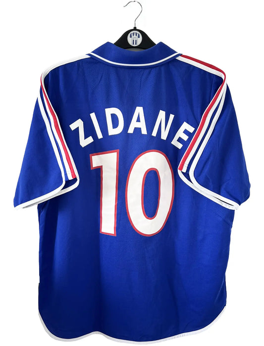 Maillot de foot vintage domicile de l'équipe de france 2000. Le maillot est de couleur bleu blanc et rouge. On peut retrouver l'équipementier adidas. Le maillot est floqué du numéro 10 Zinedine Zidane. Il s'agit d'un maillot authentique comportant les numéros 647194.
