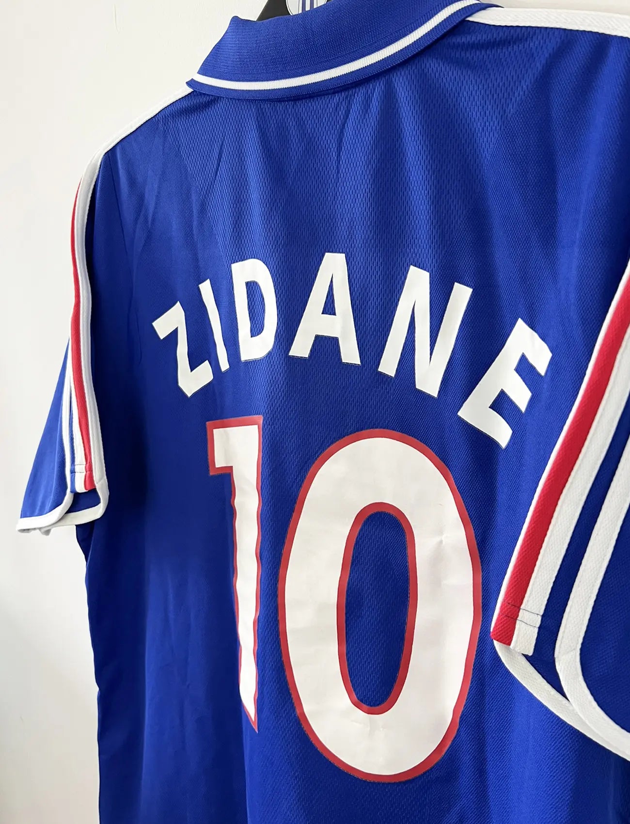 Maillot de foot vintage domicile de l'équipe de france 2000. Le maillot est de couleur bleu blanc et rouge. On peut retrouver l'équipementier adidas. Le maillot est floqué du numéro 10 Zinedine Zidane. Il s'agit d'un maillot authentique comportant les numéros 647194.