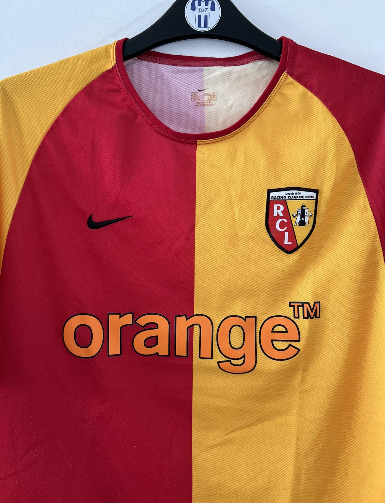 Maillot de foot vintage domicile du rc lens de la saison 2003-2004. On peut retrouver l'équipementier nike et le sponsor Orange. Le maillot est de couleur jaune et rouge. Il s'agit d'un maillot authentique comportant l'étiquette avec les numéros 112760
