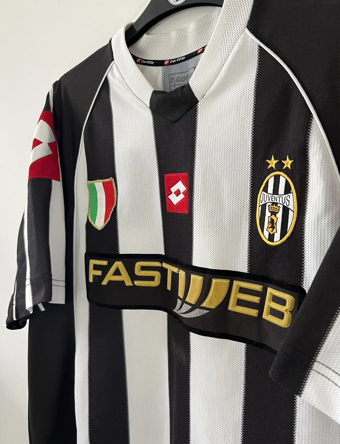 Maillot de foot vintage domicile noir et blanc de la juventus de turin de la saison 2002/2003. On peut retrouver l'équipementier lotto et le sponsor fastweb. Il s'agit d'un maillot authentique d'époque.