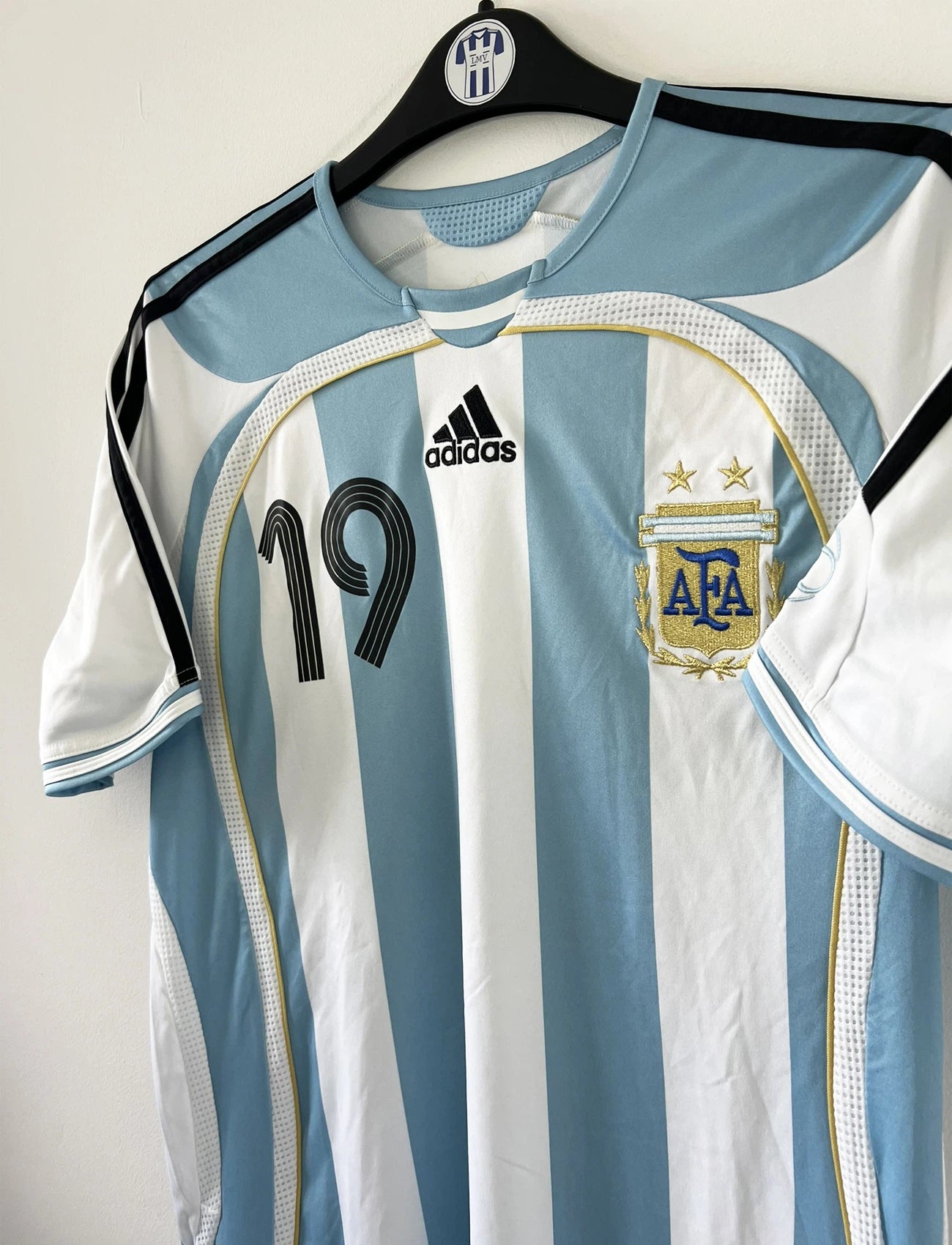 Maillot de foot vintage de l'argentine de la coupe du monde 2006. Le maillot est de couleur bleu et blanc. On peut retrouver l'équipementier adidas. Le maillot est floqué du numéro 19 Lionel Messi. Il s'agit d'un maillot authentique comportant les numéros 739802.