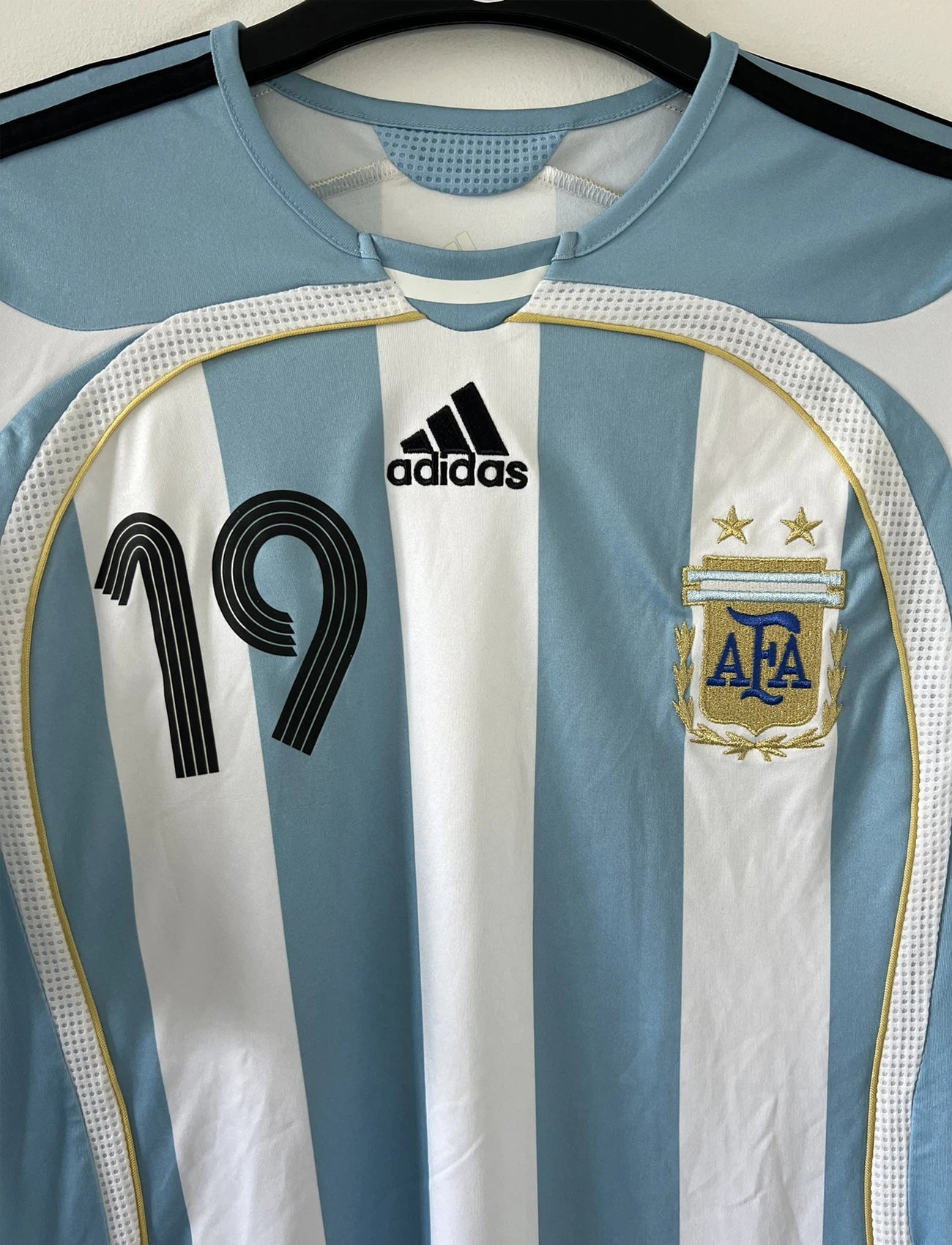 Maillot de foot vintage de l'argentine de la coupe du monde 2006. Le maillot est de couleur bleu et blanc. On peut retrouver l'équipementier adidas. Le maillot est floqué du numéro 19 Lionel Messi. Il s'agit d'un maillot authentique comportant les numéros 739802.