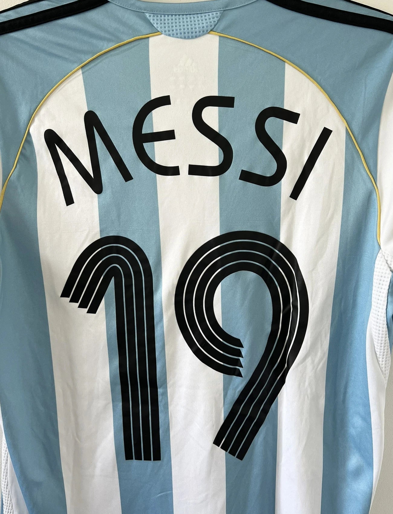 Maillot de foot vintage de l'argentine de la coupe du monde 2006. Le maillot est de couleur bleu et blanc. On peut retrouver l'équipementier adidas. Le maillot est floqué du numéro 19 Lionel Messi. Il s'agit d'un maillot authentique comportant les numéros 739802.