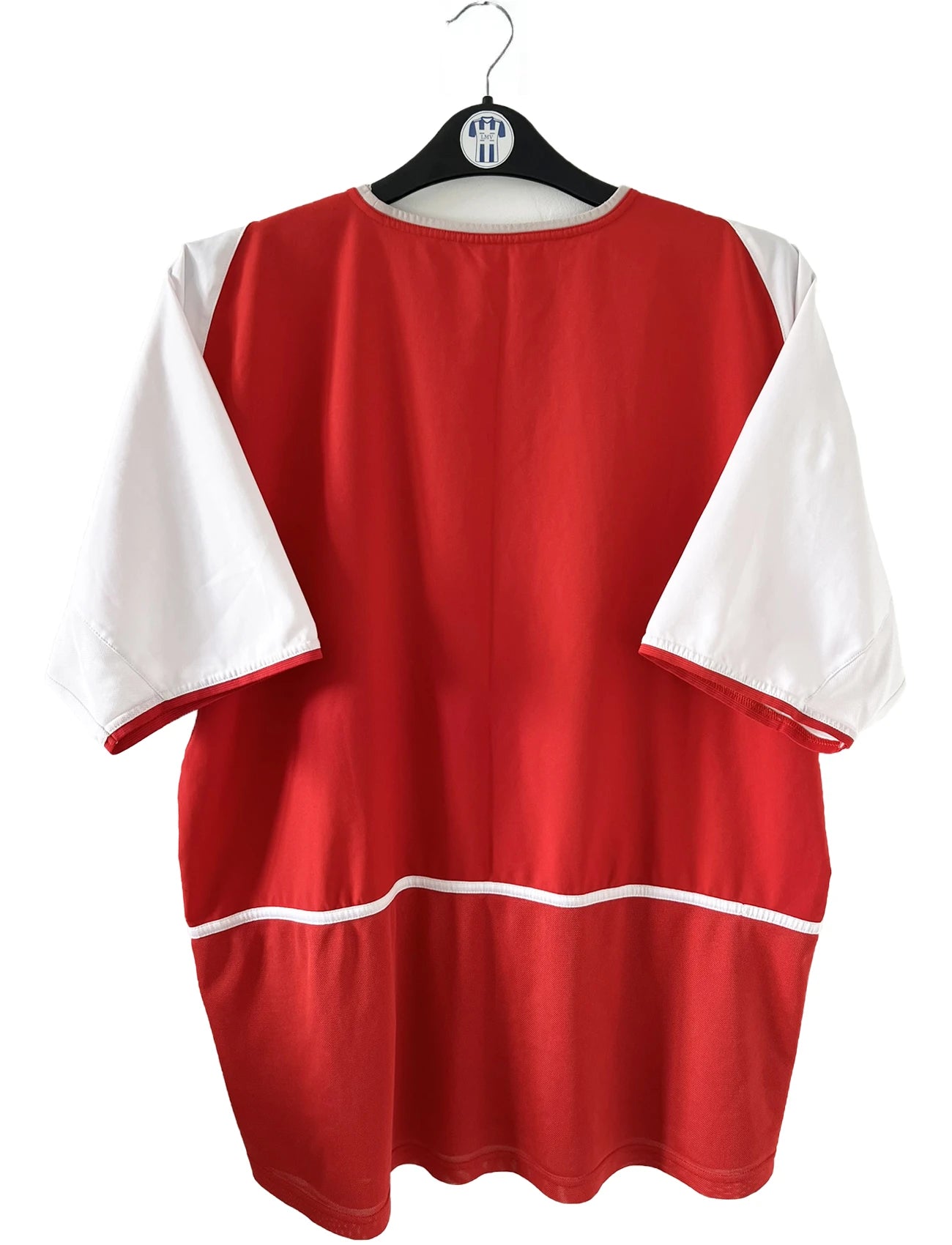 Maillot domicile Arsenal rouge et blanc de la saison 2002-2004. On peut retrouver l'équipementier nike et le sponsor O2. Il s'agit d'un maillot authentique d'époque comportant l'étiquette 184985