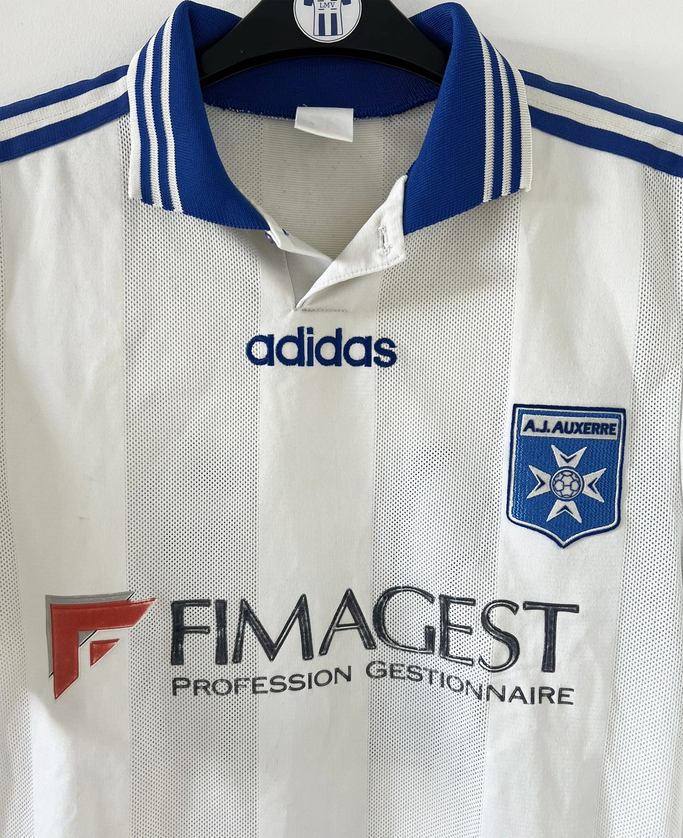 Maillot de foot vintage domicile blanc et bleu de l'AJ Auxerre de la saison 1997/1998. On peut retrouver l'équipementier adidas et le sponsor fimagest. Il s'agit d'un maillot authentique d'époque.