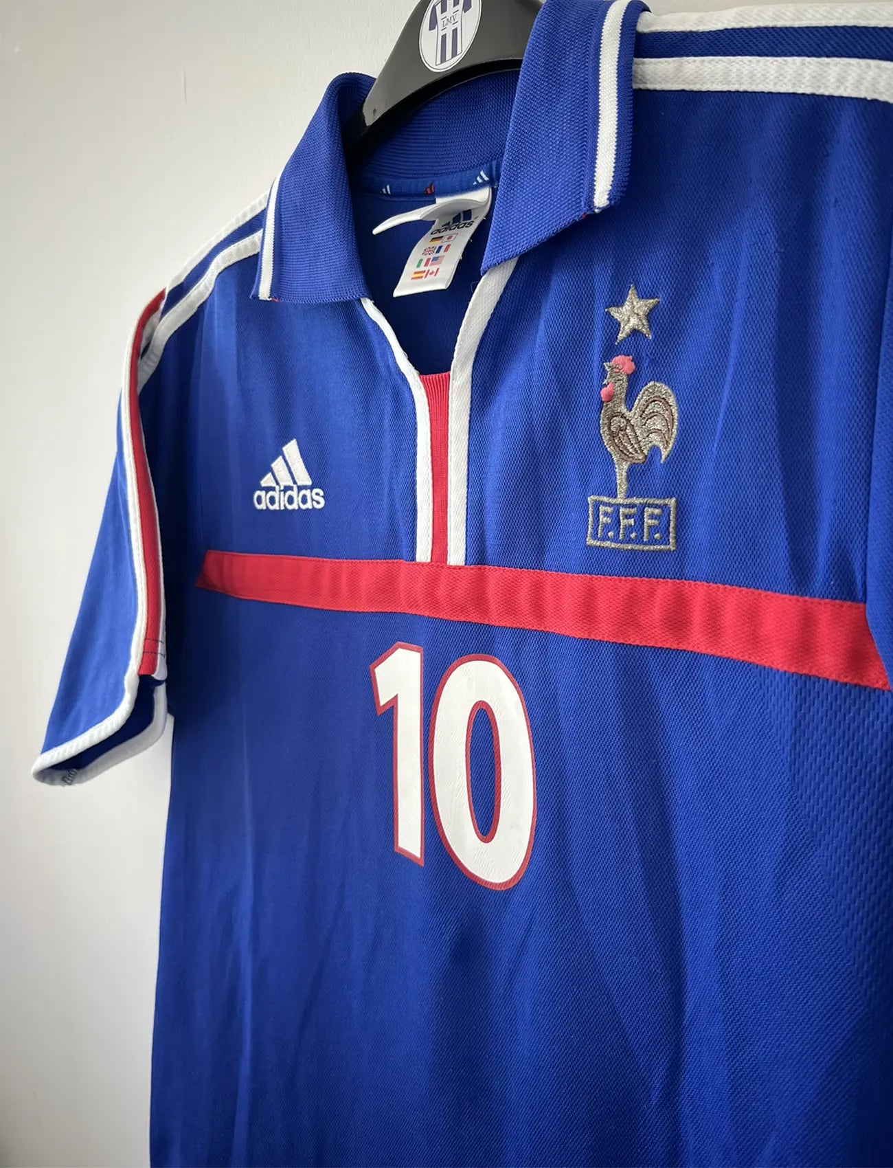 Maillot de foot vintage domicile de l'équipe de france 2000. Le maillot est de couleur bleu blanc et rouge. On peut retrouver l'équipementier adidas. Le maillot est floqué du numéro 10 Zinedine Zidane à l'avant et au dos du maillot. Il s'agit d'un maillot authentique comportant les numéros 647194.