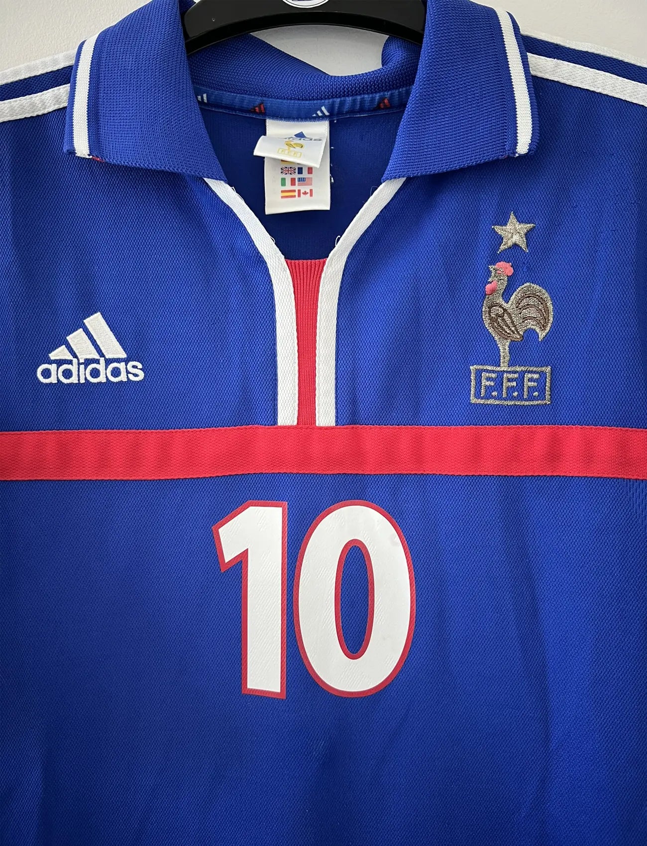 Maillot de foot vintage domicile de l'équipe de france 2000. Le maillot est de couleur bleu blanc et rouge. On peut retrouver l'équipementier adidas. Le maillot est floqué du numéro 10 Zinedine Zidane à l'avant et au dos du maillot. Il s'agit d'un maillot authentique comportant les numéros 647194.