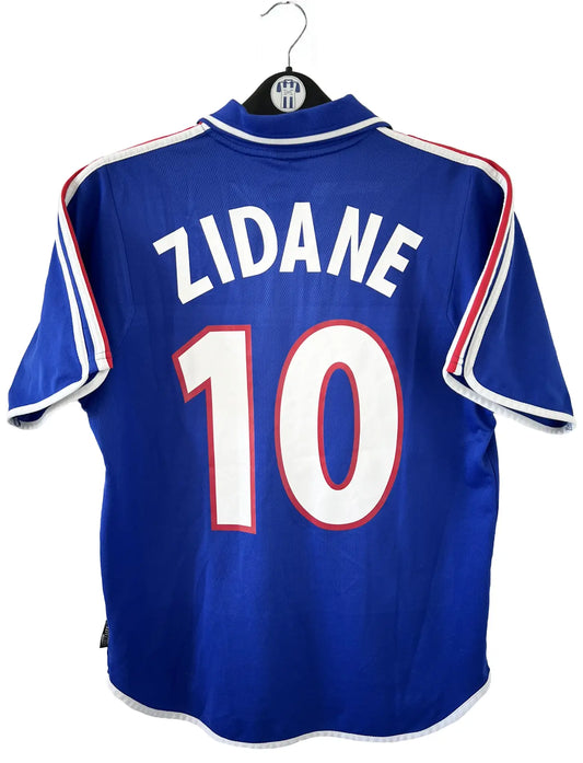 Maillot de foot vintage domicile de l'équipe de france 2000. Le maillot est de couleur bleu blanc et rouge. On peut retrouver l'équipementier adidas. Le maillot est floqué du numéro 10 Zinedine Zidane à l'avant et au dos du maillot. Il s'agit d'un maillot authentique comportant les numéros 647194.