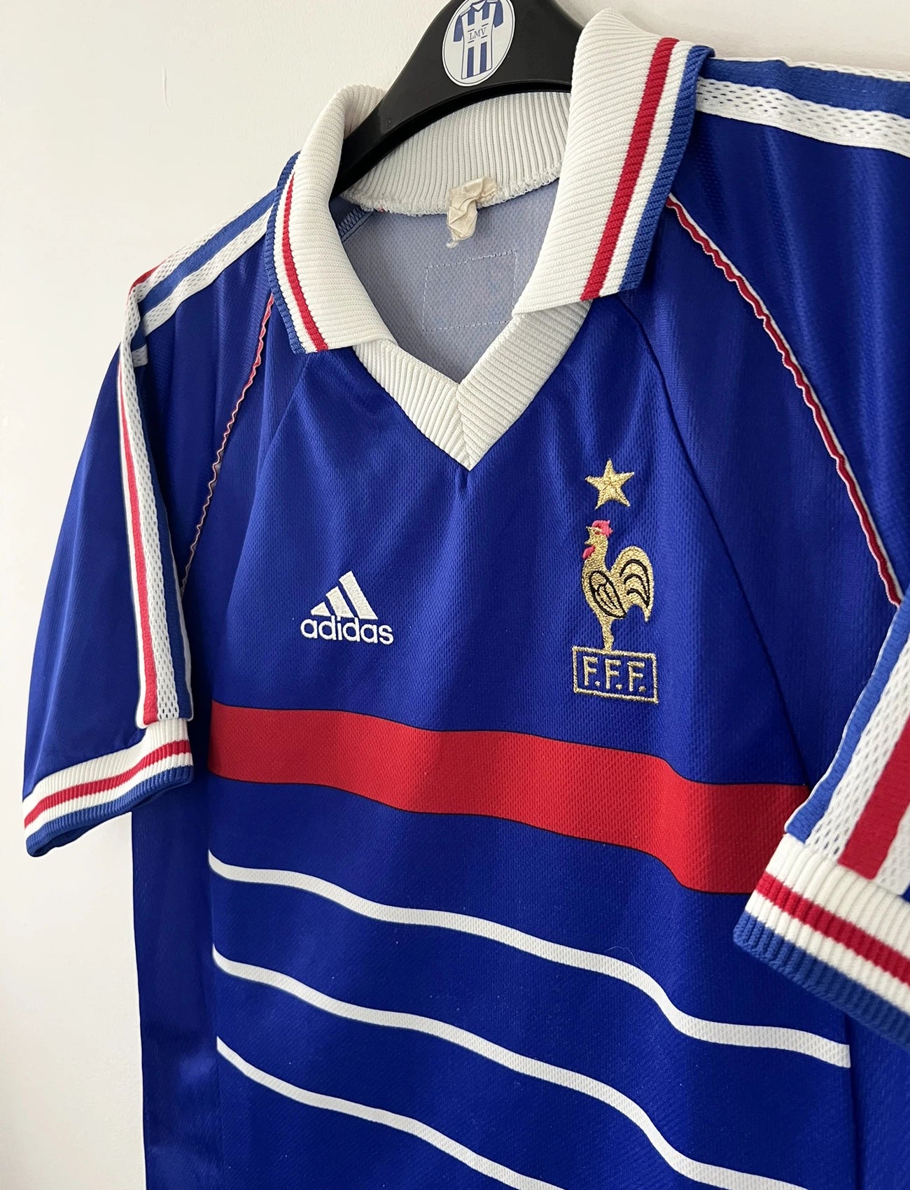 Maillot de foot vintage domicile bleu de l'Equipe de France 1998. On peut retrouver l'équipementier Adidas. Le maillot est floqué Zinedine Zidane. Il s'agit d'un maillot authentique d'époque.