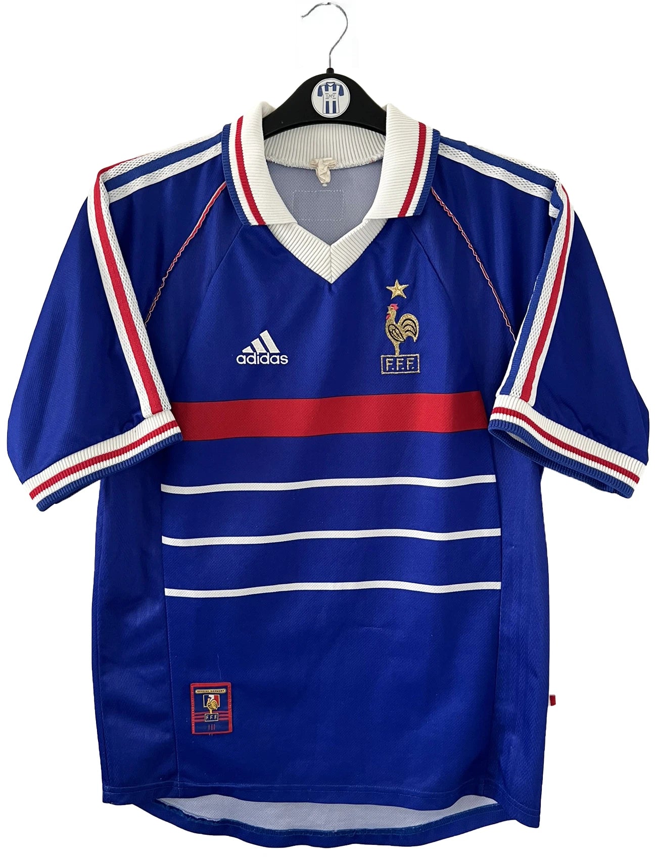 Maillot de foot vintage domicile bleu de l'Equipe de France 1998. On peut retrouver l'équipementier Adidas. Le maillot est floqué Zinedine Zidane. Il s'agit d'un maillot authentique d'époque.