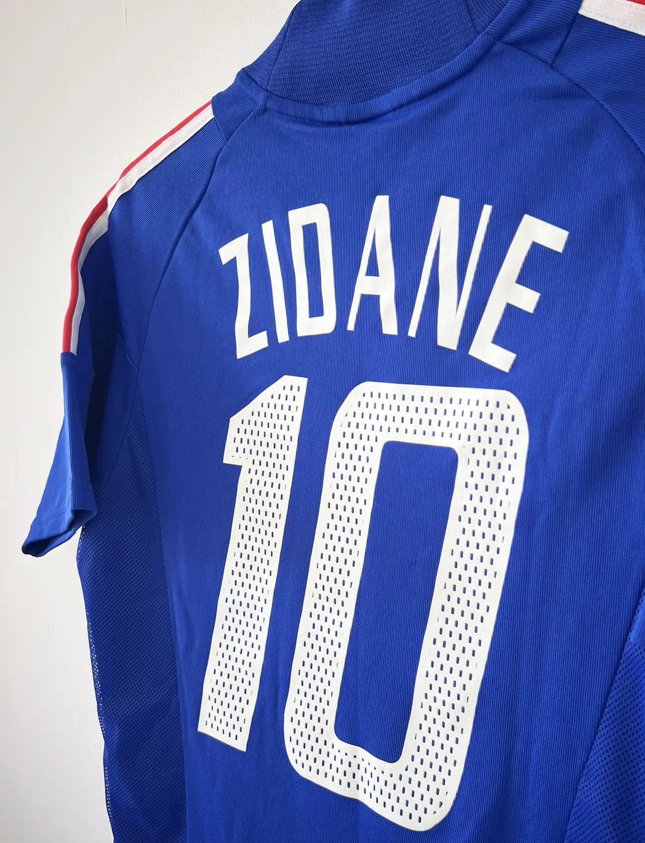 Maillot de foot vintage domicile de l'équipe de france 2002. Le maillot est de couleur bleu blanc et rouge. On peut retrouver l'équipementier adidas. Le maillot est floqué du numéro 10 Zinedine Zidane. Il s'agit d'un maillot authentique d'époque comportant les numéros 139531.
