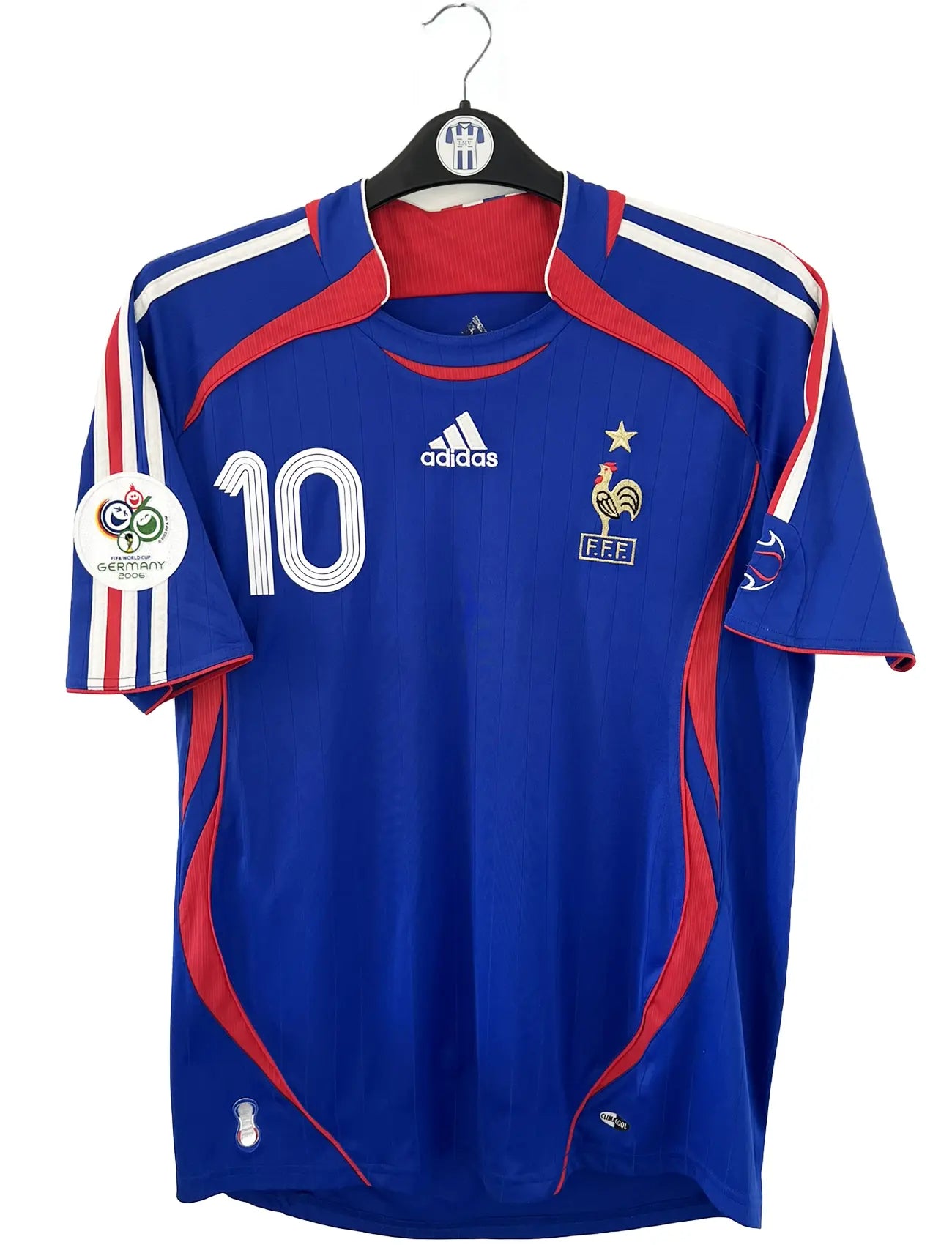 Maillot de foot vintage domicile bleu, blanc et rouge de l'équipe de france 2006. On peut retrouver l'équipementier adidas. Le maillot est floqué du numéro 10 Zinedine Zidane. Il s'agit d'un maillot authentique d'époque comportant l'étiquette 740126