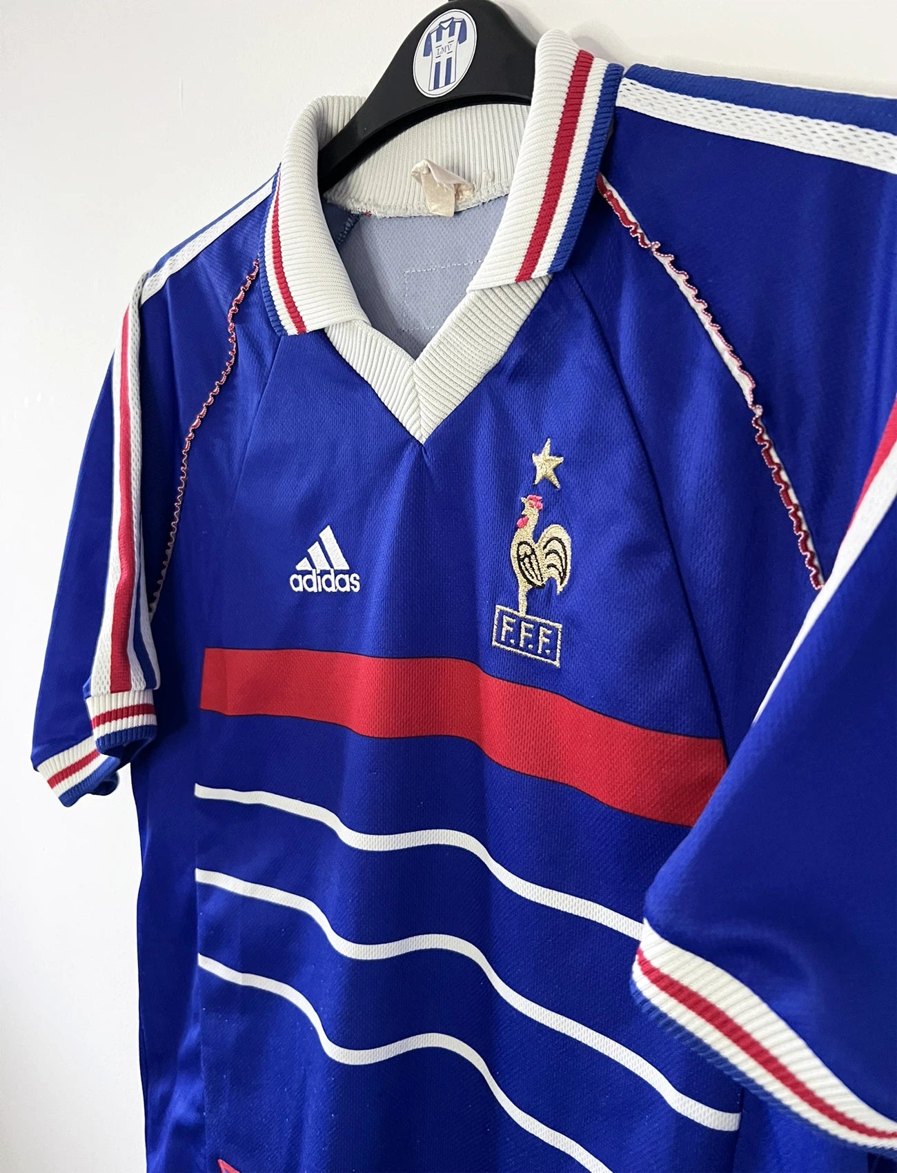 Maillot de foot vintage domicile bleu, blanc et rouge de l'équipe de france 1998. On peut retrouver l'équipementier adidas. Il s'agit d'un maillot authentique d'époque