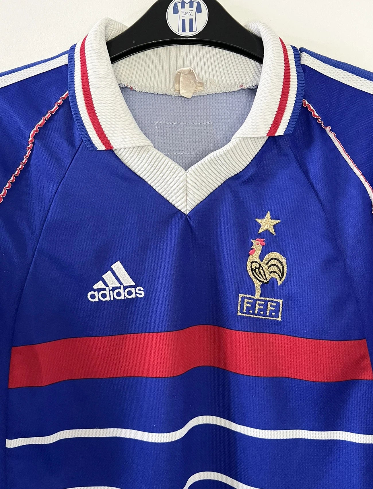 Maillot de foot vintage domicile bleu, blanc et rouge de l'équipe de france 1998. On peut retrouver l'équipementier adidas. Il s'agit d'un maillot authentique d'époque