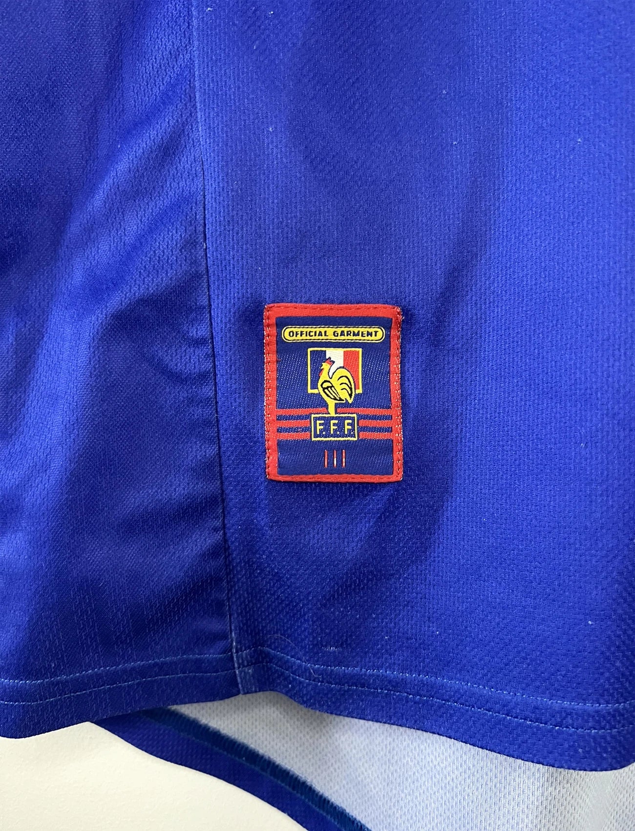 Maillot de foot vintage domicile bleu, blanc et rouge de l'équipe de france 1998. On peut retrouver l'équipementier adidas. Il s'agit d'un maillot authentique d'époque