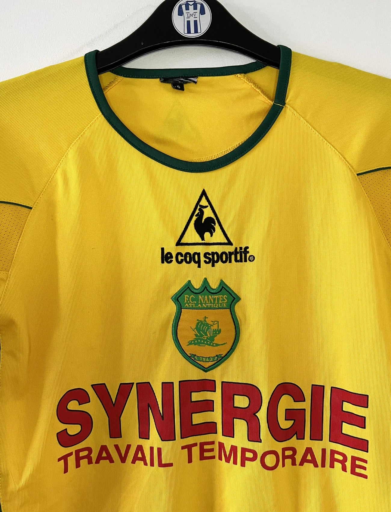 Maillot de foot vintage domicile jaune du FC Nantes de la saison 2003-2004. On peut retrouver l'équipementier Le Coq Sportif et le sponsor Synergie. Il s'agit d'un maillot authentique d'époque.