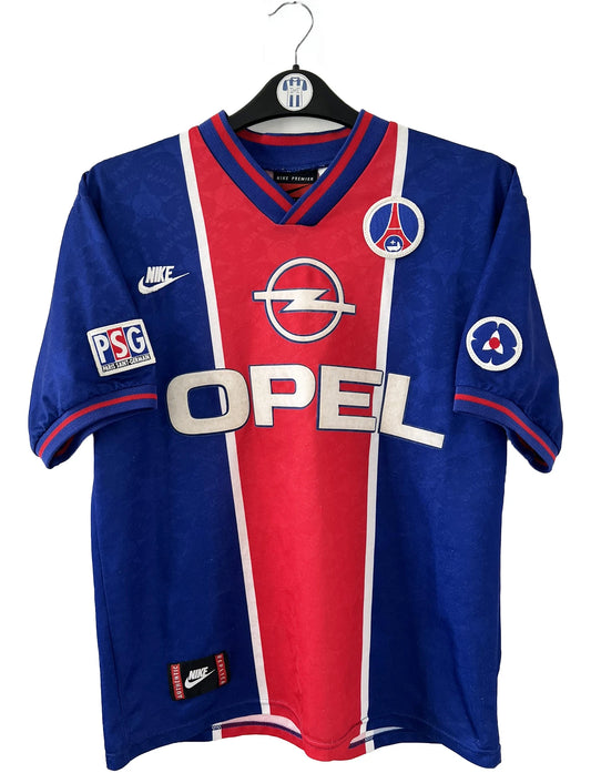 Maillot de foot vintage domicile bleu et rouge du PSG de la saison 1995/1996. On peut retrouver l'équipementier Nike et le sponsor Opel. Il s'agit d'un maillot authentique d'époque.