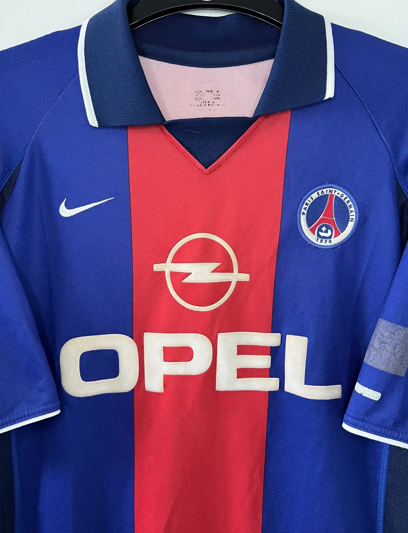 Maillot de foot vintage domicile du PSG de la saison 2000/2001. Le maillot est de couleur bleu et rouge. On peut retrouver l'équipementier nike et le sponsor OPEL