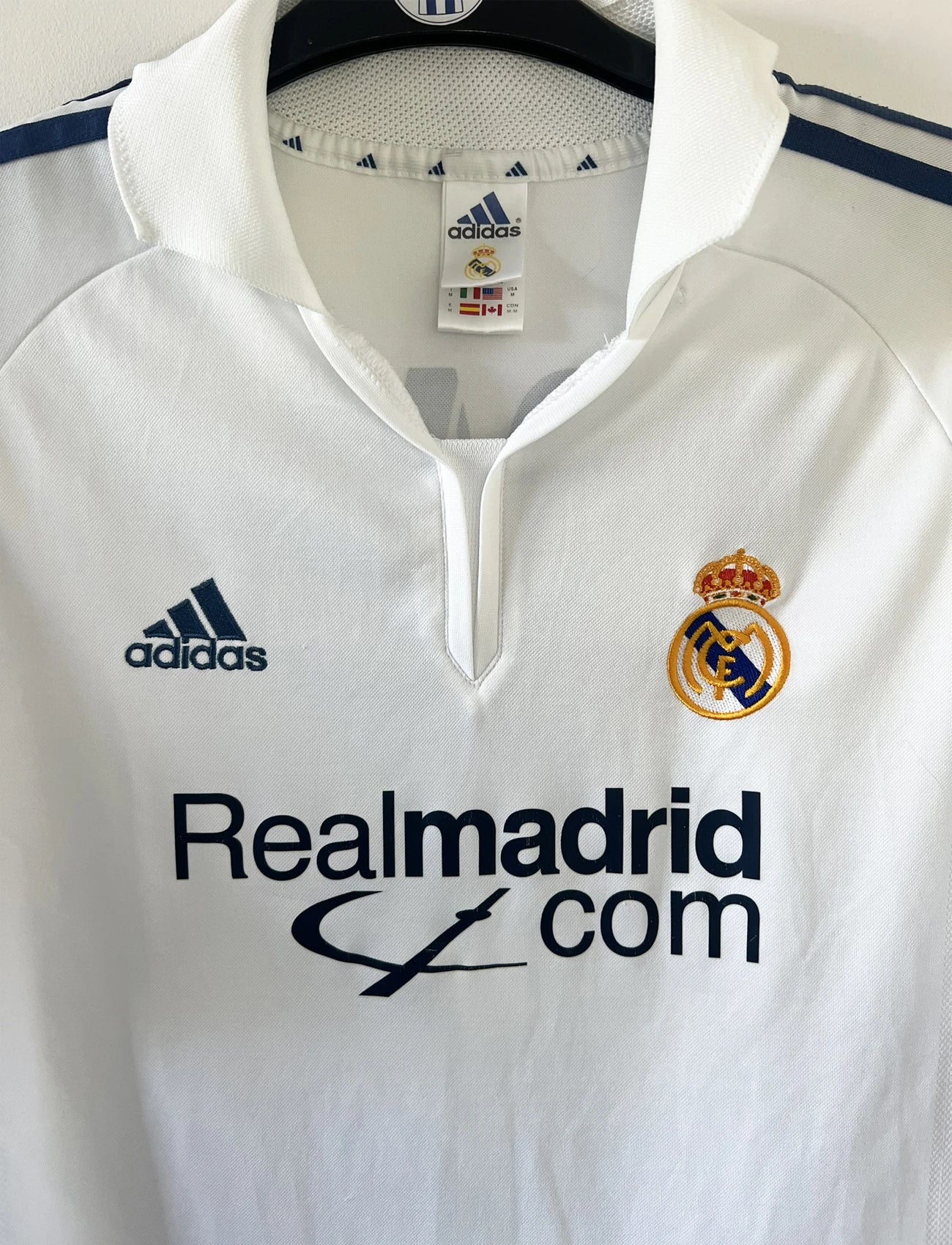 Maillot de foot vintage domicile du real madrid de la saison 2001-2002. Le maillot est de couleur blanc et noir. On peut retrouver l'équipementier adidas et le sponsor Real Madrid.com. Le maillot est floqué du numéro 5 Zinedine Zidane. Il s'agit d'un maillot authentique comportant les numéros 695856