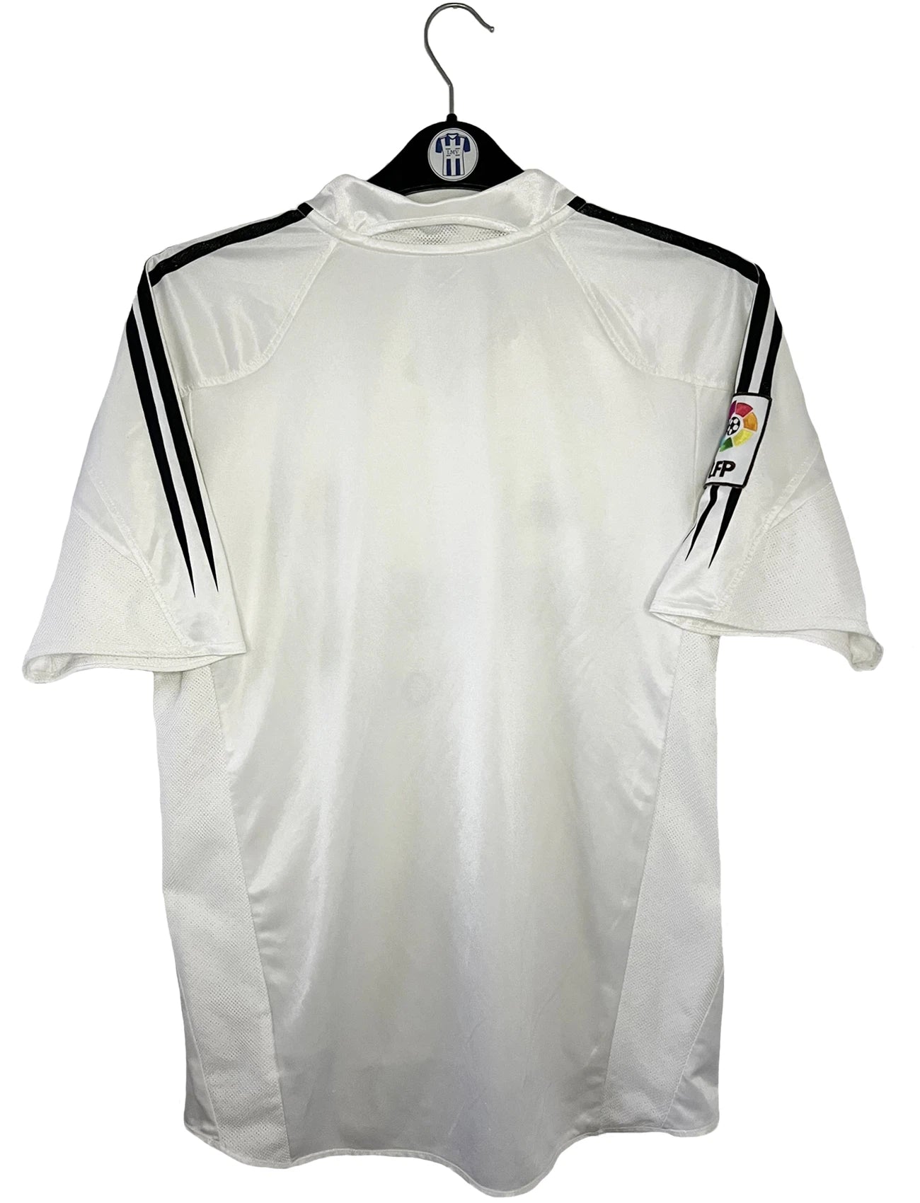 Maillot de foot vintage domicile blanc du real madrid de la saison 2004/2005. On peut retrouver l'équipementier Adidas et le sponsor Siemens. Il s'agit d'un maillot authentique d'époque comportant l'étiquette 367842