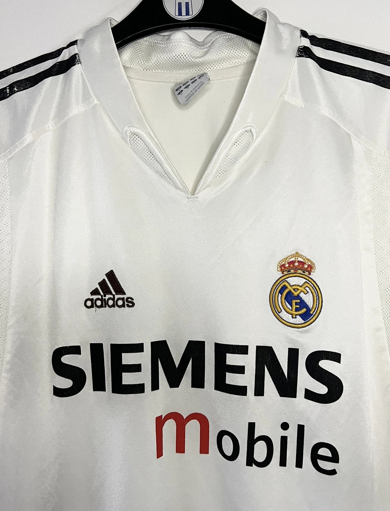 Maillot de foot vintage domicile blanc du real madrid de la saison 2004/2005. On peut retrouver l'équipementier Adidas et le sponsor Siemens. Il s'agit d'un maillot authentique d'époque comportant l'étiquette 367842