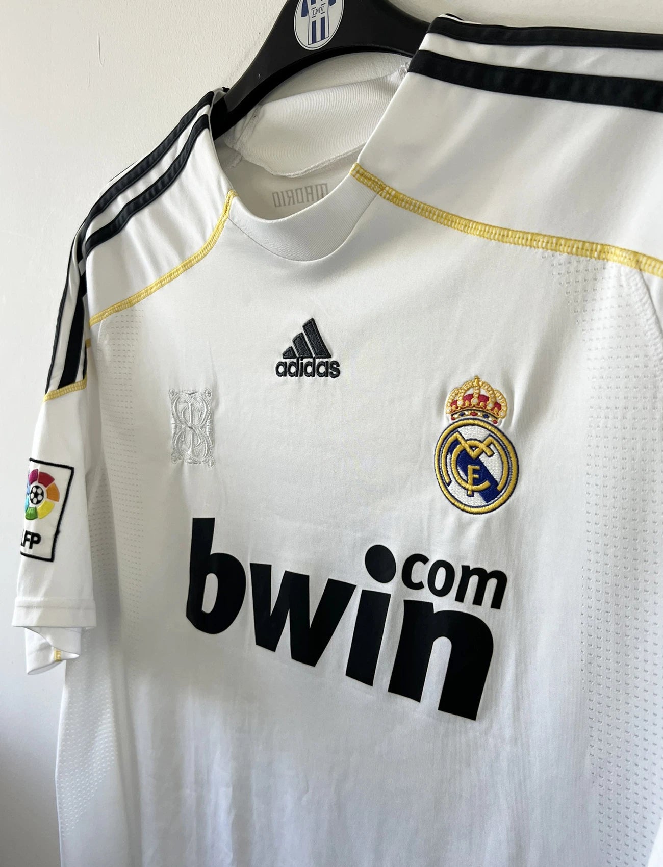 Maillot de foot vintage domicile du real madrid blanc de la saison 2009/2010. On peut retrouver l'équipementier adidas et le sponsor bwin. Le maillot est floqué du numéro 9 Cistiano Ronaldo. Il s'agit d'un maillot authentique comportant les numéros E84352