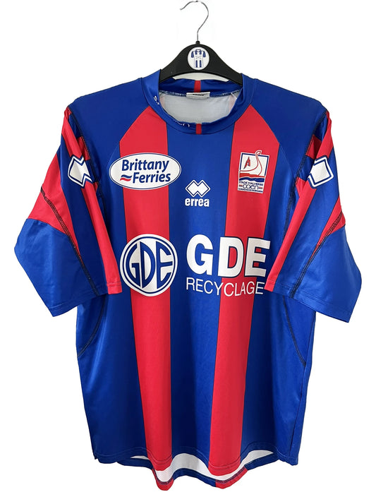 Maillot de foot vintage domicile bleu et rouge du SM Caen de la saison 2006/2007. On peut retrouver l'équipementier Errea et le sponsor Brittany Ferries et GDE. Il s'agit d'un maillot authentique d'époque.