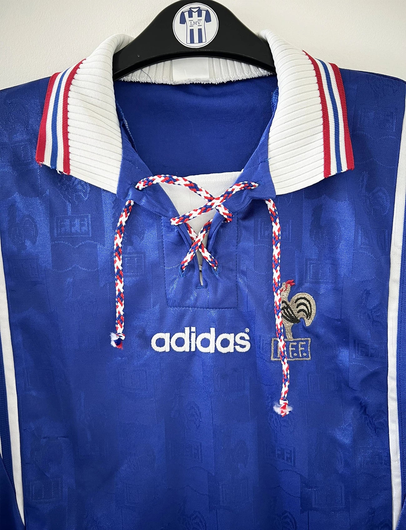 Maillot de foot vintage domicile de l'équipe de france 1996 de couleur bleu blanc et rouge. On peut retrouver l'équipementier adidas et le coq sans étoile. Il s'agit d'un maillot authentique d'époque.