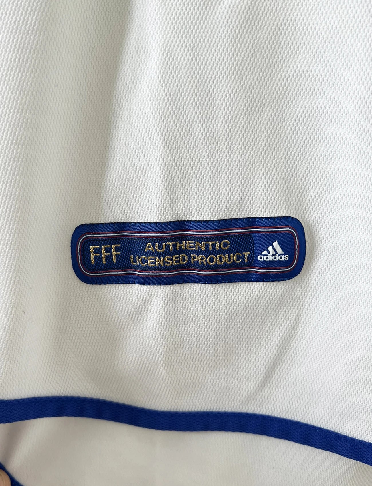 Maillot de foot vintage extérieur blanc de l'équipe de france 2000. On peut retrouver l'équipementier adidas. Il s'agit d'un maillot authentique d'époque comportant l'étiquette 647189.