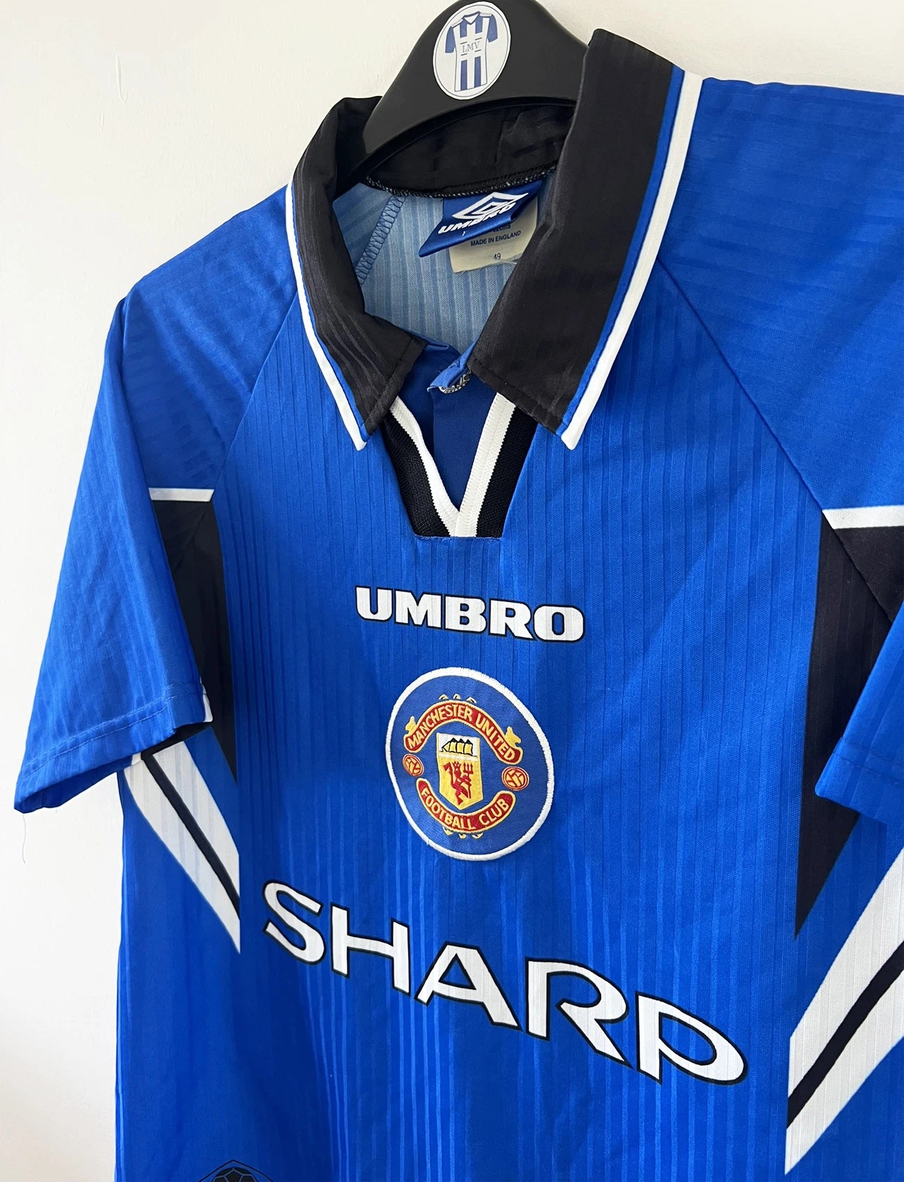 Maillot de foot vintage extérieur bleu de manchester united de la saison 1996-1998. On peut retrouver l'équipementier umbro et le sponsor sharp. Il s'agit d'un maillot autentique d'époque.