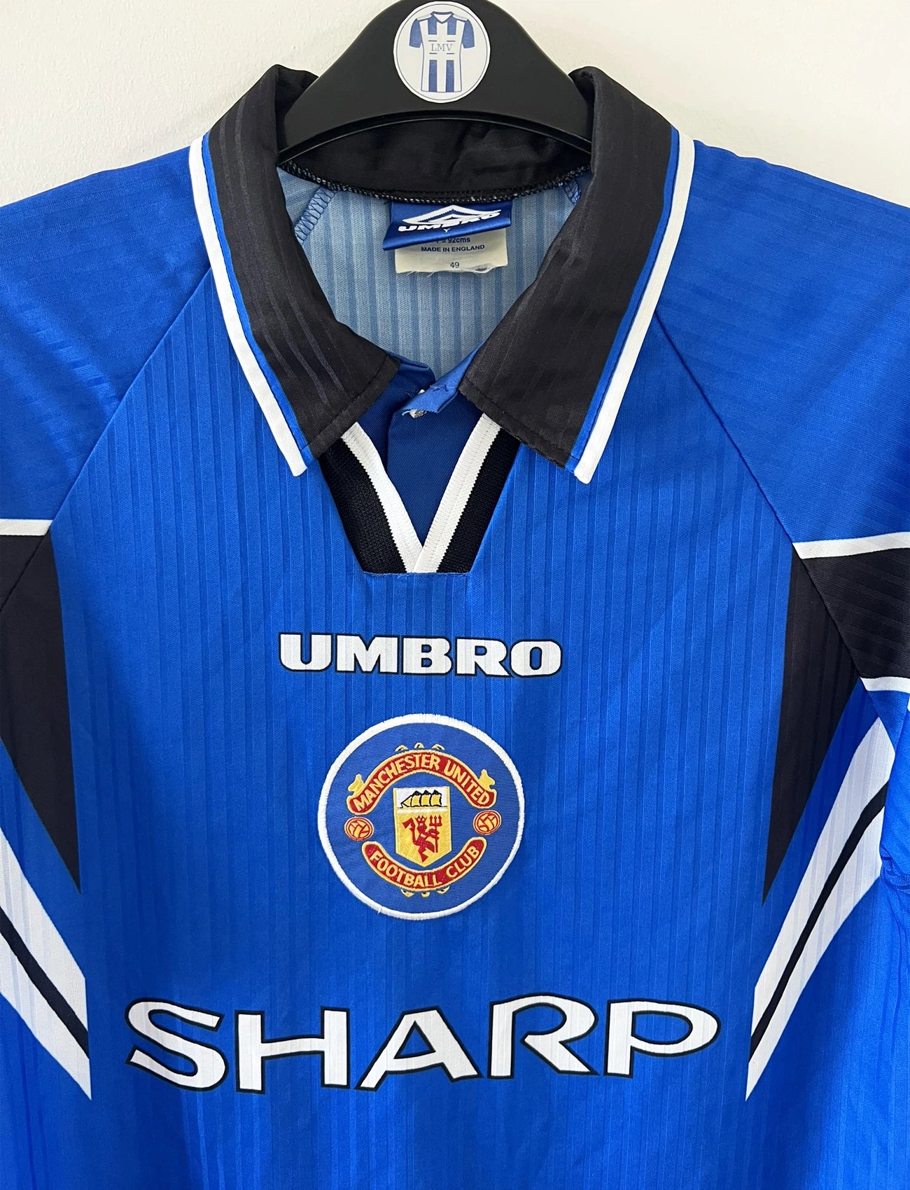 Maillot de foot vintage extérieur bleu de manchester united de la saison 1996-1998. On peut retrouver l'équipementier umbro et le sponsor sharp. Il s'agit d'un maillot autentique d'époque.