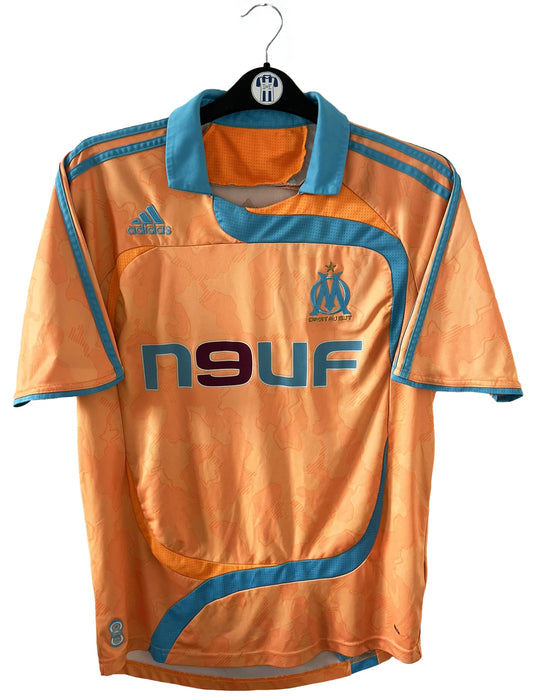 Maillot de foot vintage extérieur orange et bleu de l'OM de la saison 2007/2008. On peut retrouver l'équipementier Adidas et le sponsor Neuf. Il s'agit d'un maillot authentique comportant l'étiquette 695659