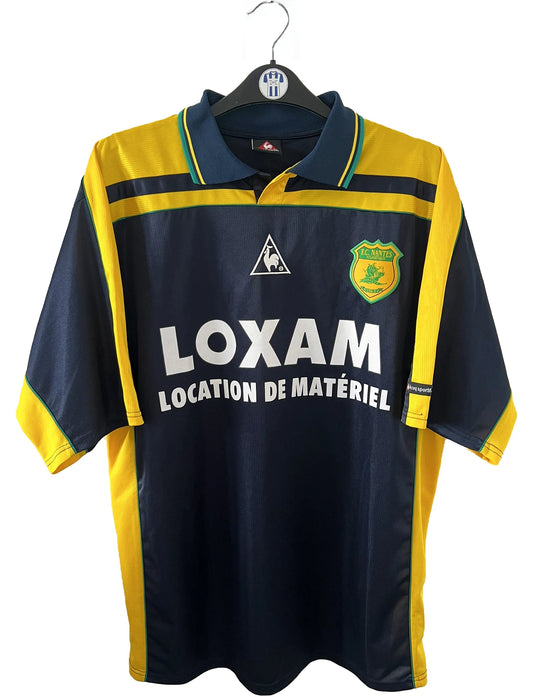 Maillot de foot vintage extérieur bleu et jaune du FC Nantes de la saison 2000-2001. On peut retrouver l'équipementier Le Coq Sportif et le sponsor Loxam. Le maillot est floqué du numéro 8 correspondant à Frédéric Da Rocha. Il s'agit d'un maillot authentique d'époque.