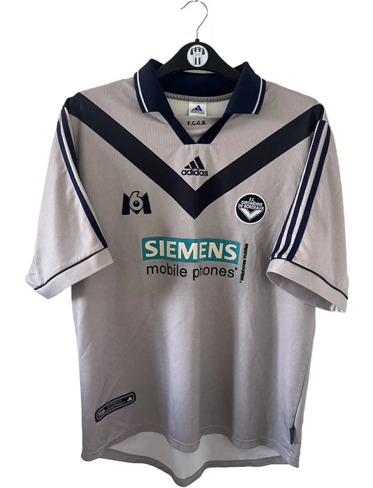 Maillot de foot vintage extérieur gris et bleu des girondins de bordeaux de la saison 2000/2001. On peut retrouver l'équipementier adidas et le sponsor Siemens et M6. Il s'agit d'un maillot authentique d'époque comportant l'étiquette 693826.